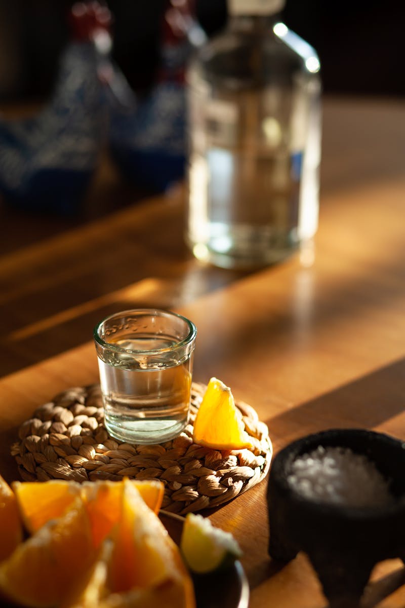 A tequila shot with an orange slice on a woven mat alongside salt, capturing a vibrant Mexican dining scene.